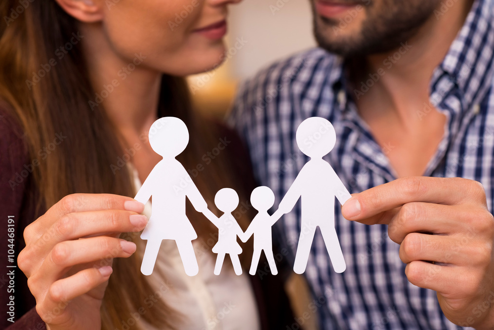 parents holding a paper cutout of a family